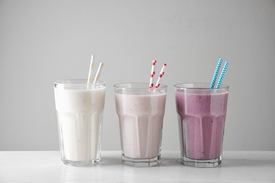 Different tasty milk shakes in glasses on white table