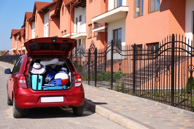 Photo of Family car with open trunk full of luggage in city. Space for text
