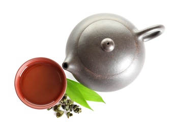 Teapot near cup of Tie Guan Yin oolong and leaves on white background, top view