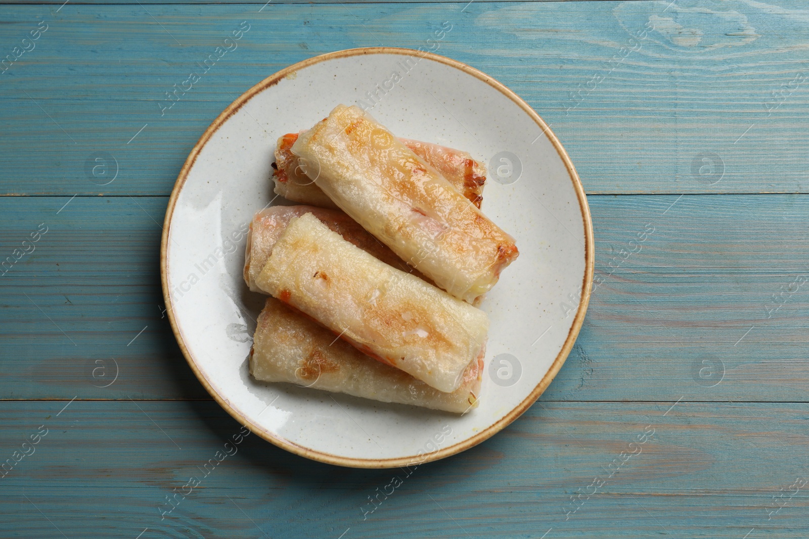 Photo of Delicious fried spring rolls on light blue wooden table, top view