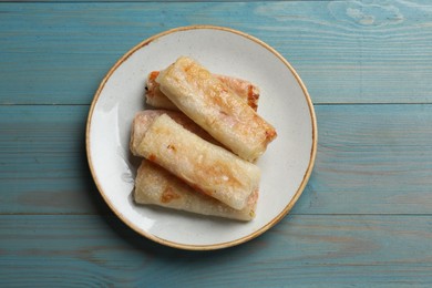 Photo of Delicious fried spring rolls on light blue wooden table, top view