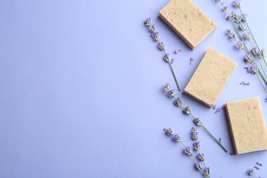 Hand made soap bars with lavender flowers on violet background, flat lay. Space for text