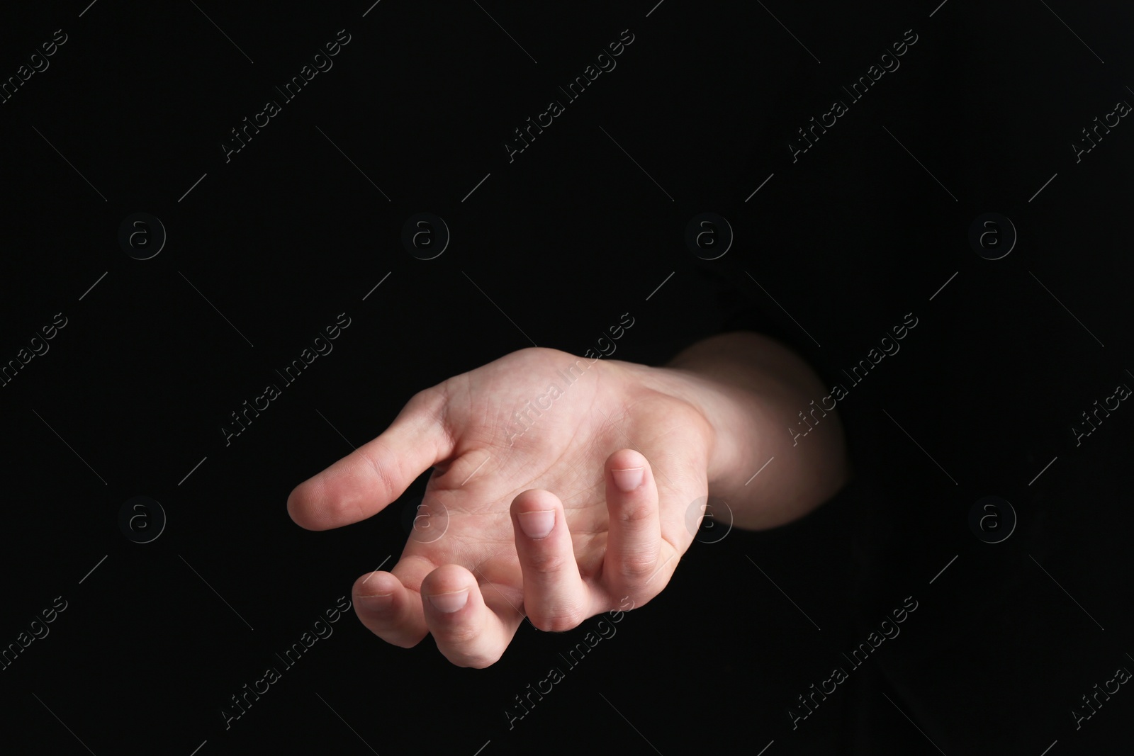 Photo of Man holding something in his hand on black background, closeup