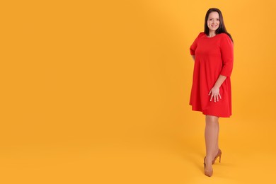 Photo of Beautiful overweight woman in red dress on yellow background. Space for text