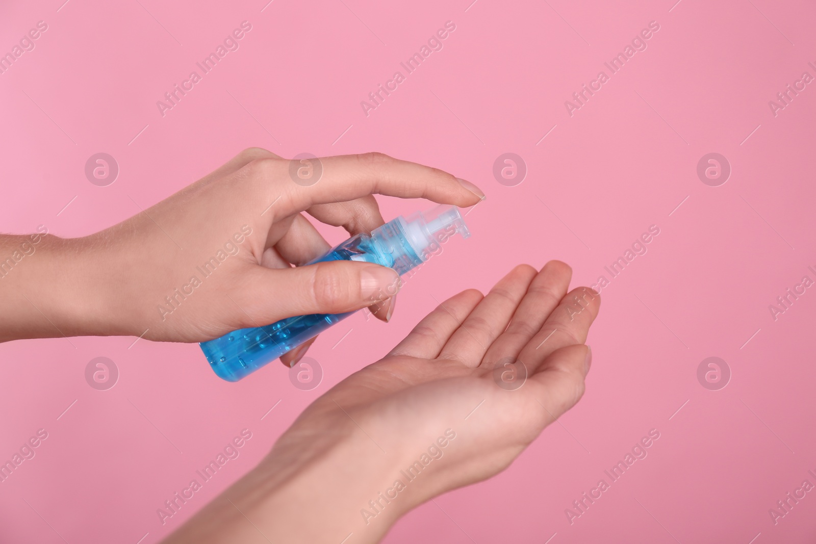 Photo of Woman applying antiseptic gel on pink background, closeup