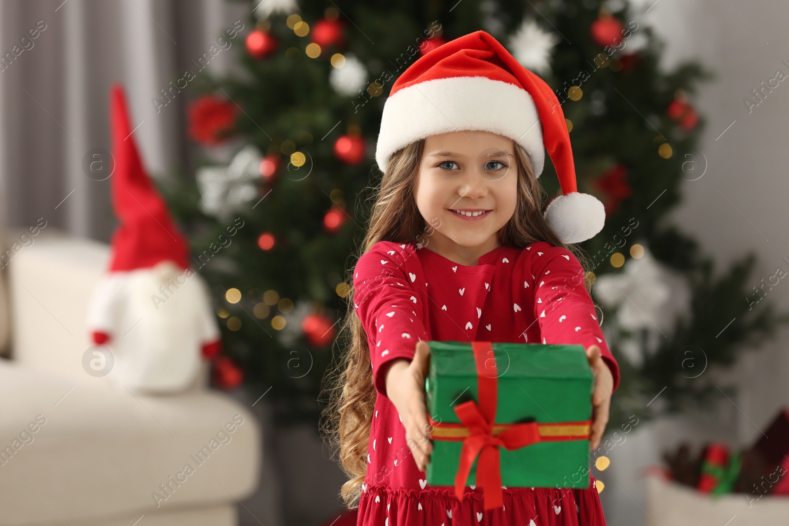 Photo of Happy girl showing Christmas gift at home. Space for text