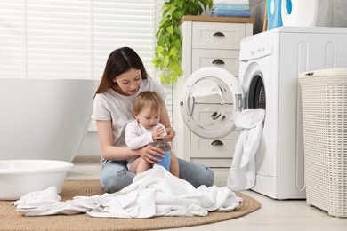 Mother with her daughter washing baby clothes in bathroom