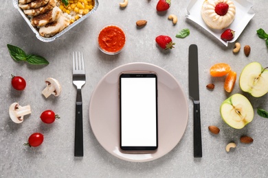 Photo of Flat lay composition with Smartphone and products on grey table, mockup for design. Healthy food delivery