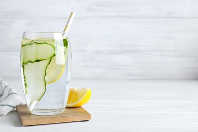Photo of Refreshing water with cucumber, lemon and mint on white table, space for text