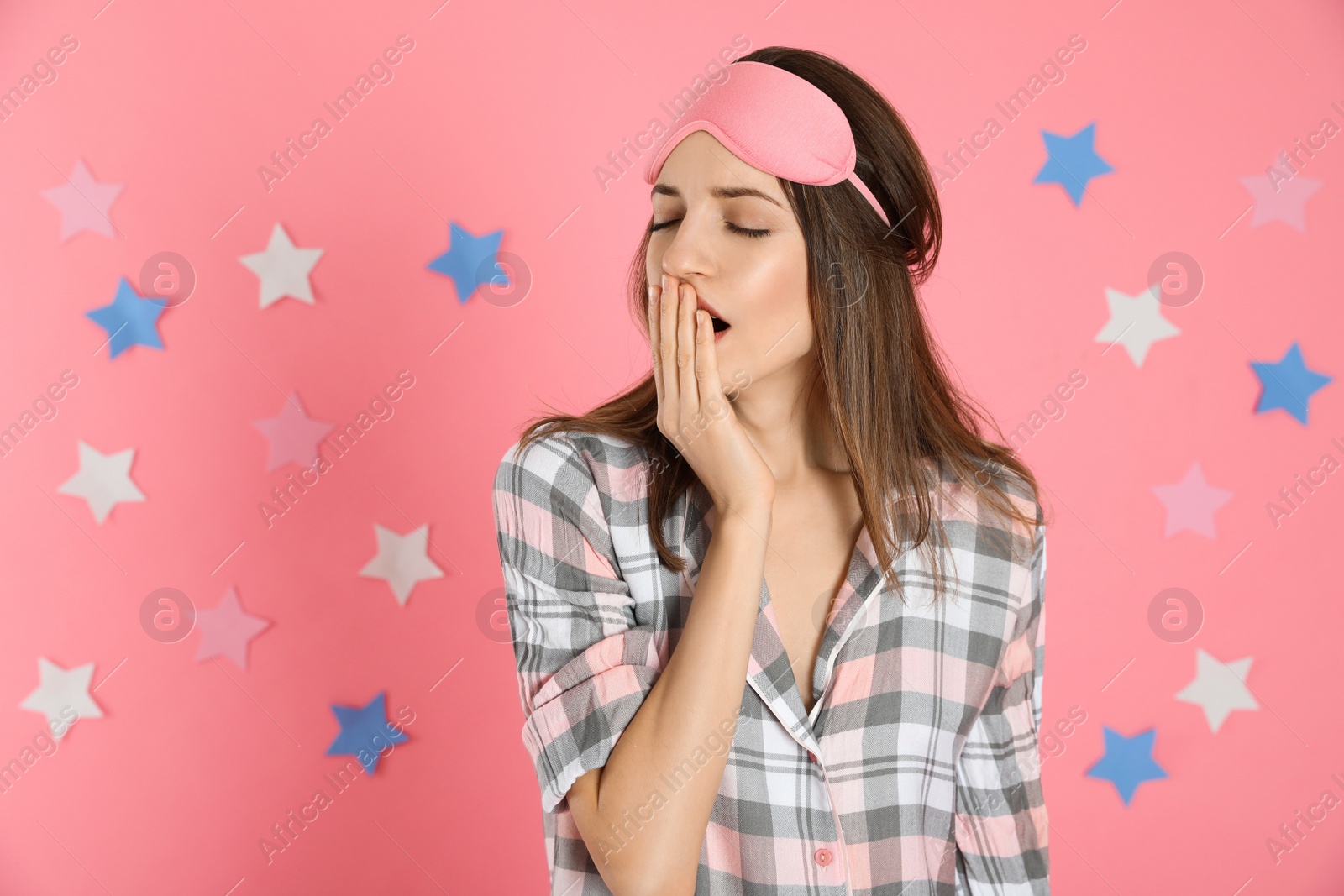Photo of Beautiful woman wearing pajamas and sleep mask on pink background. Bedtime