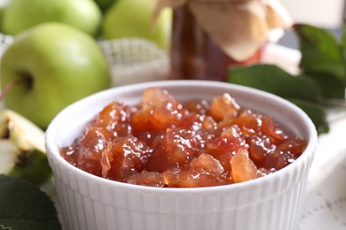 Photo of Bowl of delicious apple jam and fresh fruits on white tablecloth, closeup