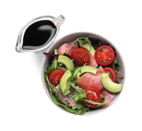 Tasty soy sauce and bowl with salad isolated on white, top view