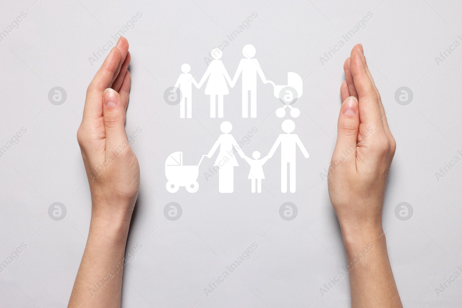 Image of Woman holding hands around cutout paper silhouette of families on light grey background, top view. Insurance concept