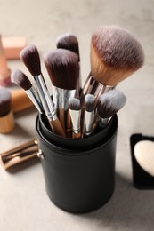 Photo of Set of professional brushes and makeup products on grey table