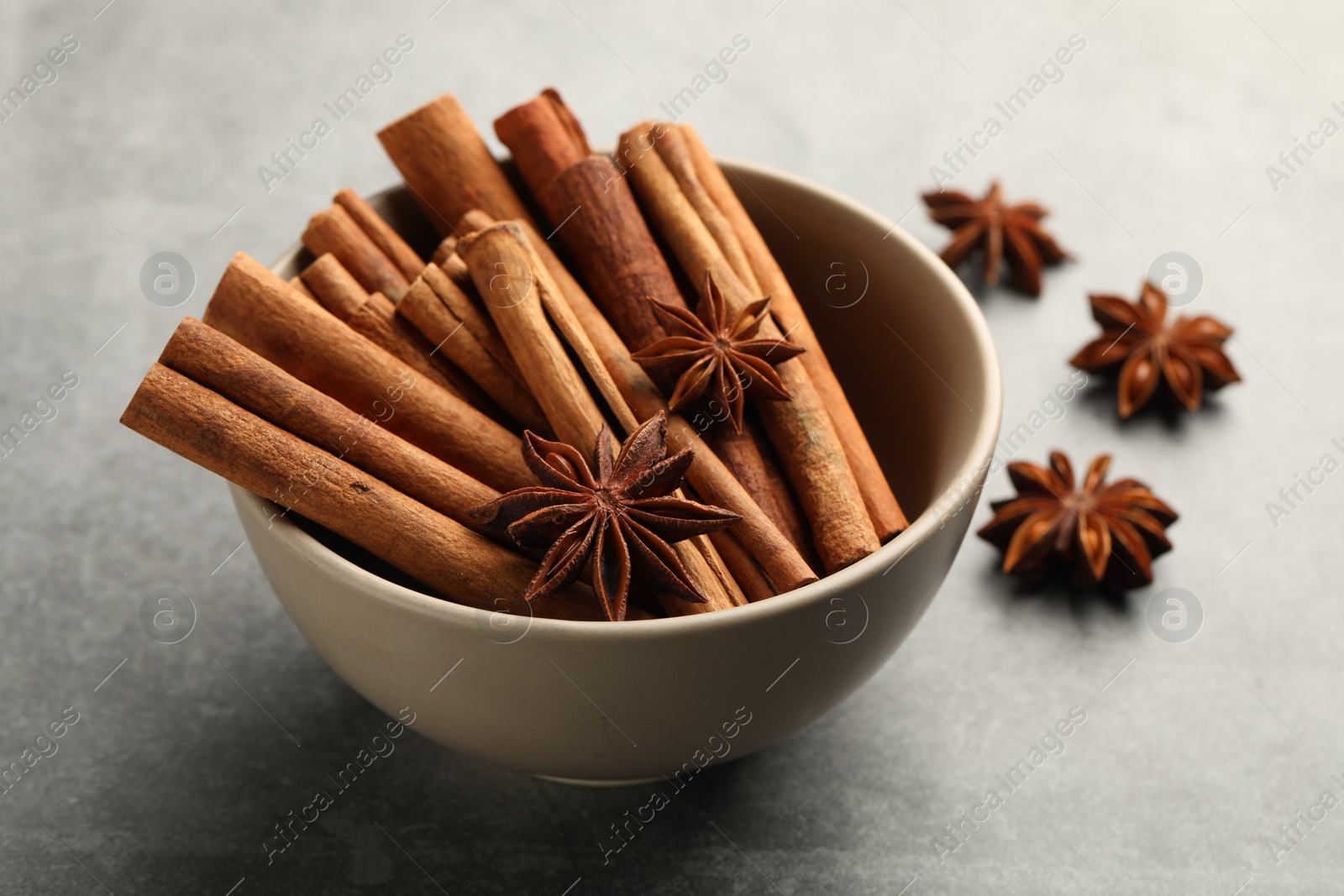 Photo of Bowl of cinnamon sticks and star anise on grey table