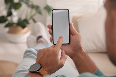 Man using mobile phone with empty screen indoors, closeup