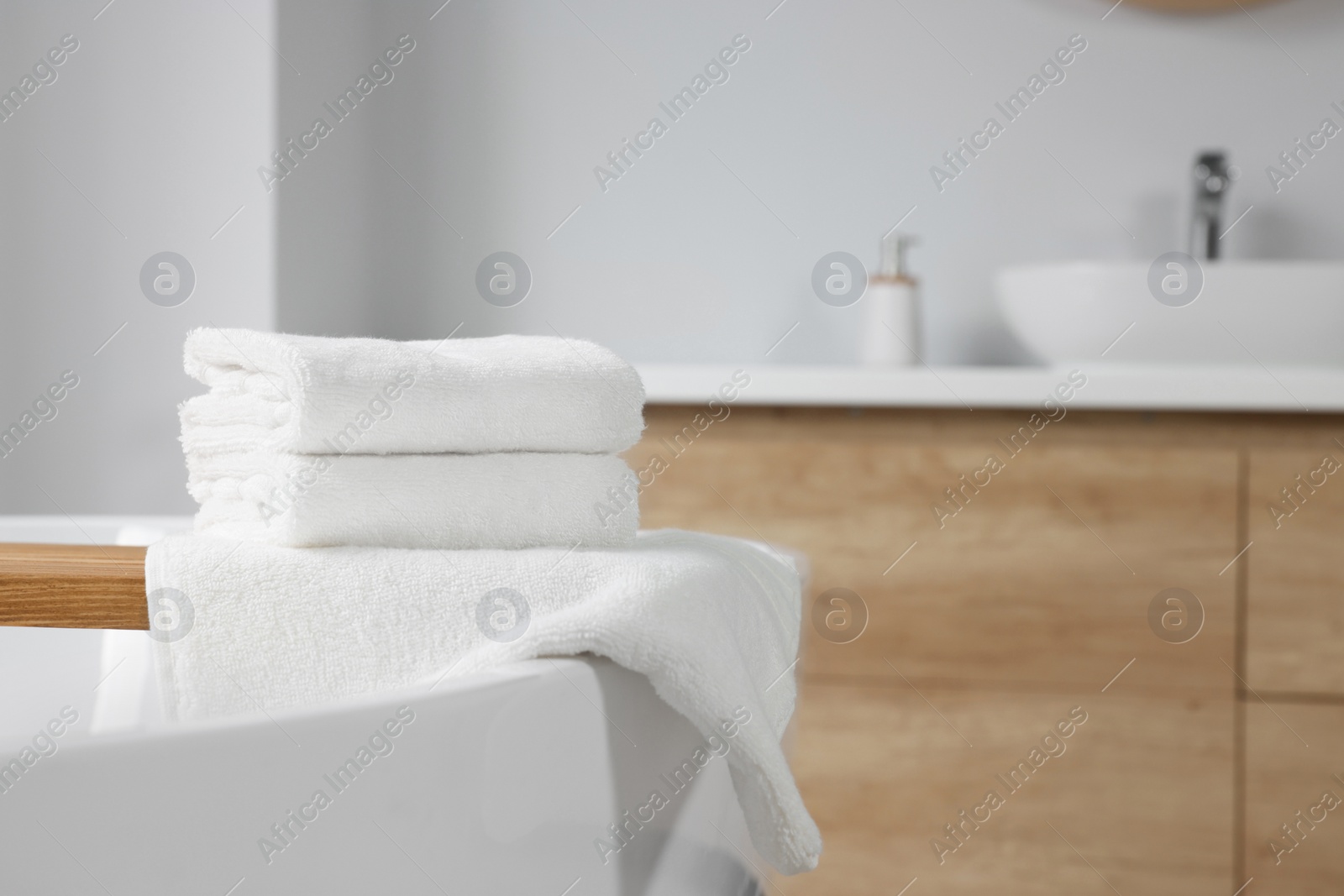 Photo of Fresh white towels on tub in bathroom. Space for text