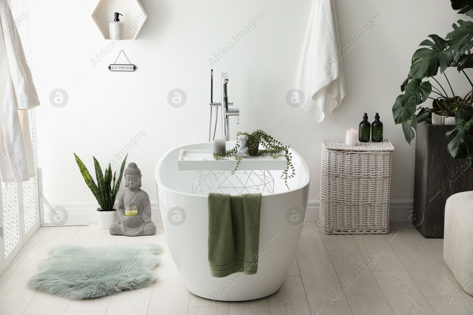 Photo of Stylish bathroom interior with modern tub, houseplants and beautiful decor. Home design