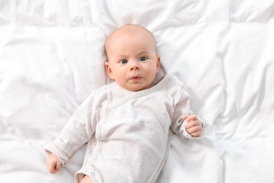Cute little baby lying on white sheets, top view