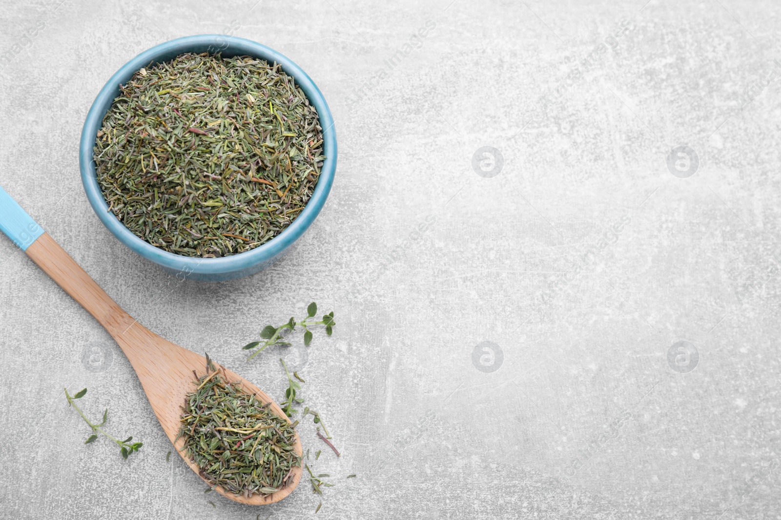 Photo of Bowl and spoon with dried thyme on grey table, flat lay. Space for text