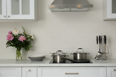 Photo of Kitchen counter with set of dishware, utensils and beautiful bouquet. Interior design