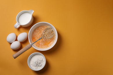 Making dough. Beaten eggs in bowl, flour and milk on orange background, flat lay. Space for text