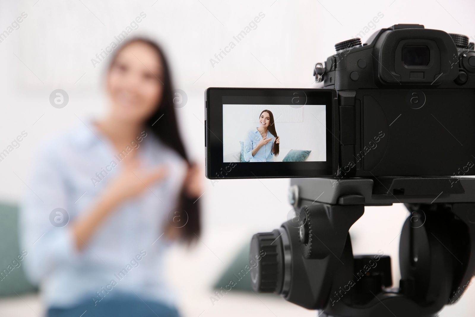 Photo of Young blogger recording video at cafe, focus on camera screen