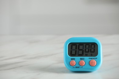 Kitchen timer on white marble table against blurred background. Space for text