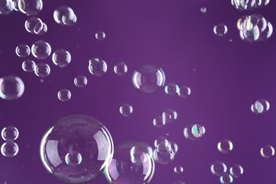 Photo of Beautiful transparent soap bubbles on purple background