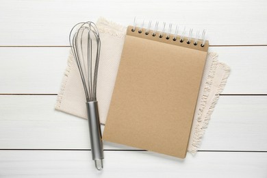 Photo of Blank recipe book and whisk on white wooden table, flat lay. Space for text