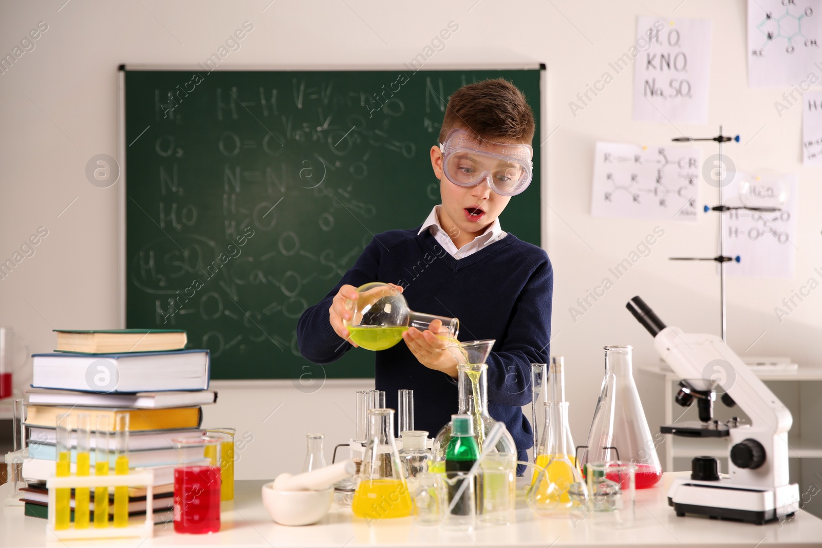 Photo of Schoolchild making experiment at table in chemistry class