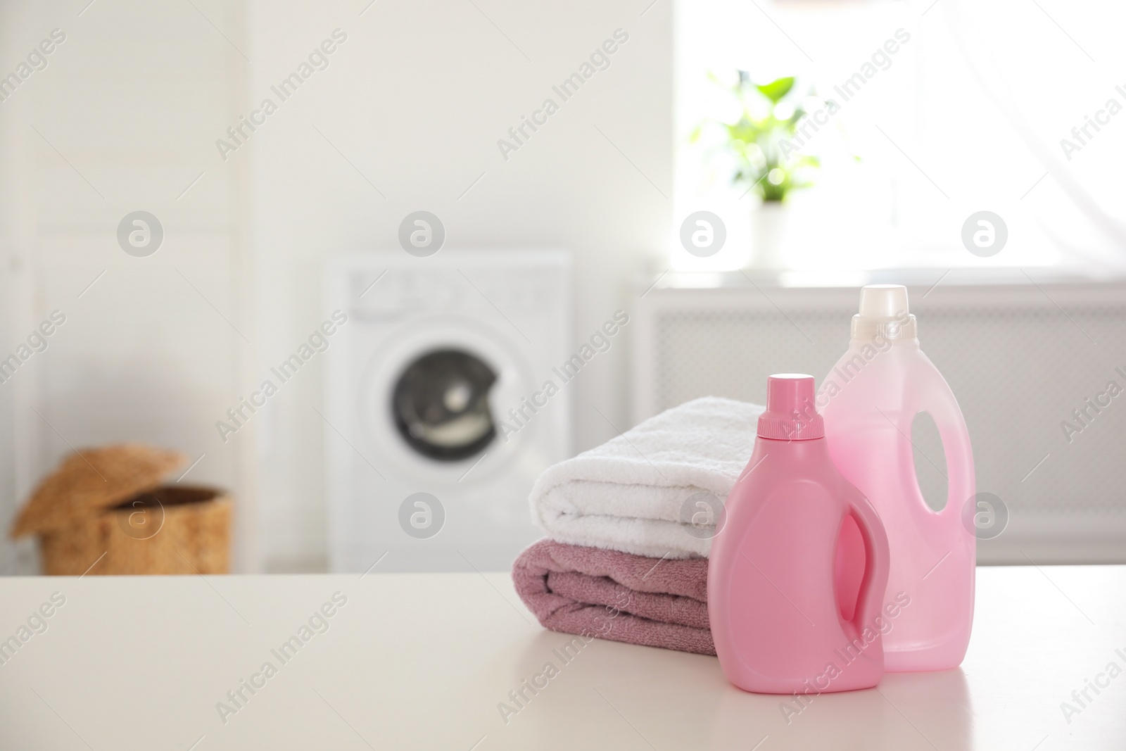 Photo of Stack of clean towels and detergents on white table indoors. Space for text