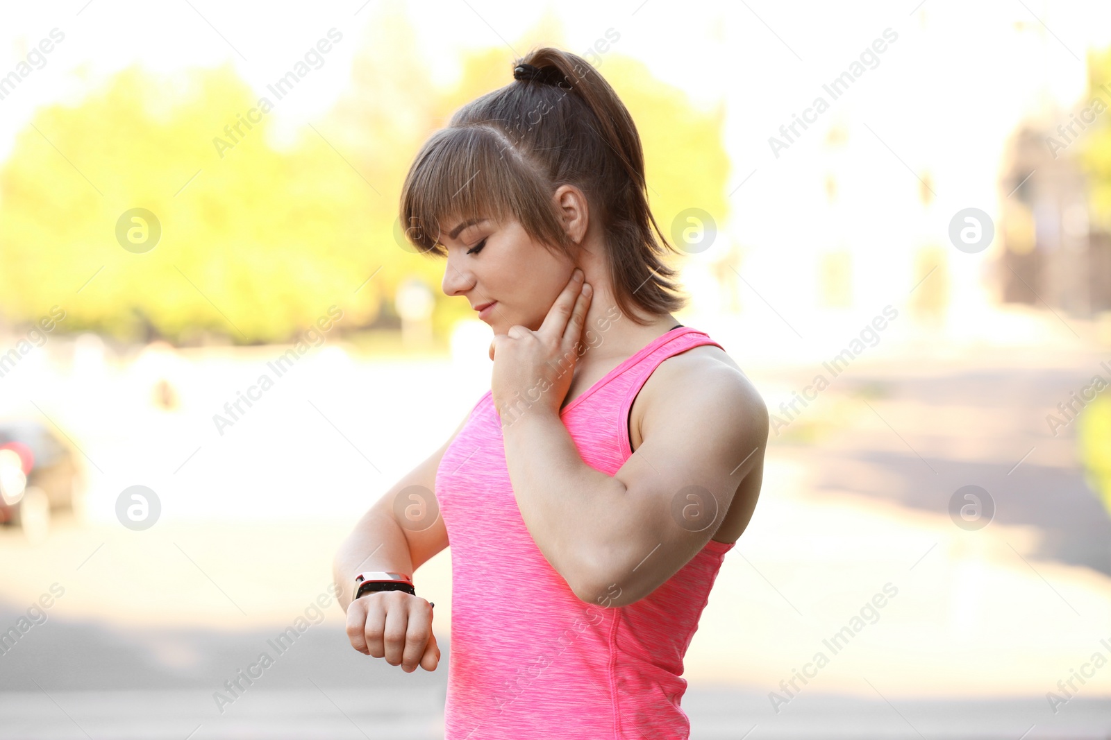 Photo of Young woman checking pulse after workout in park