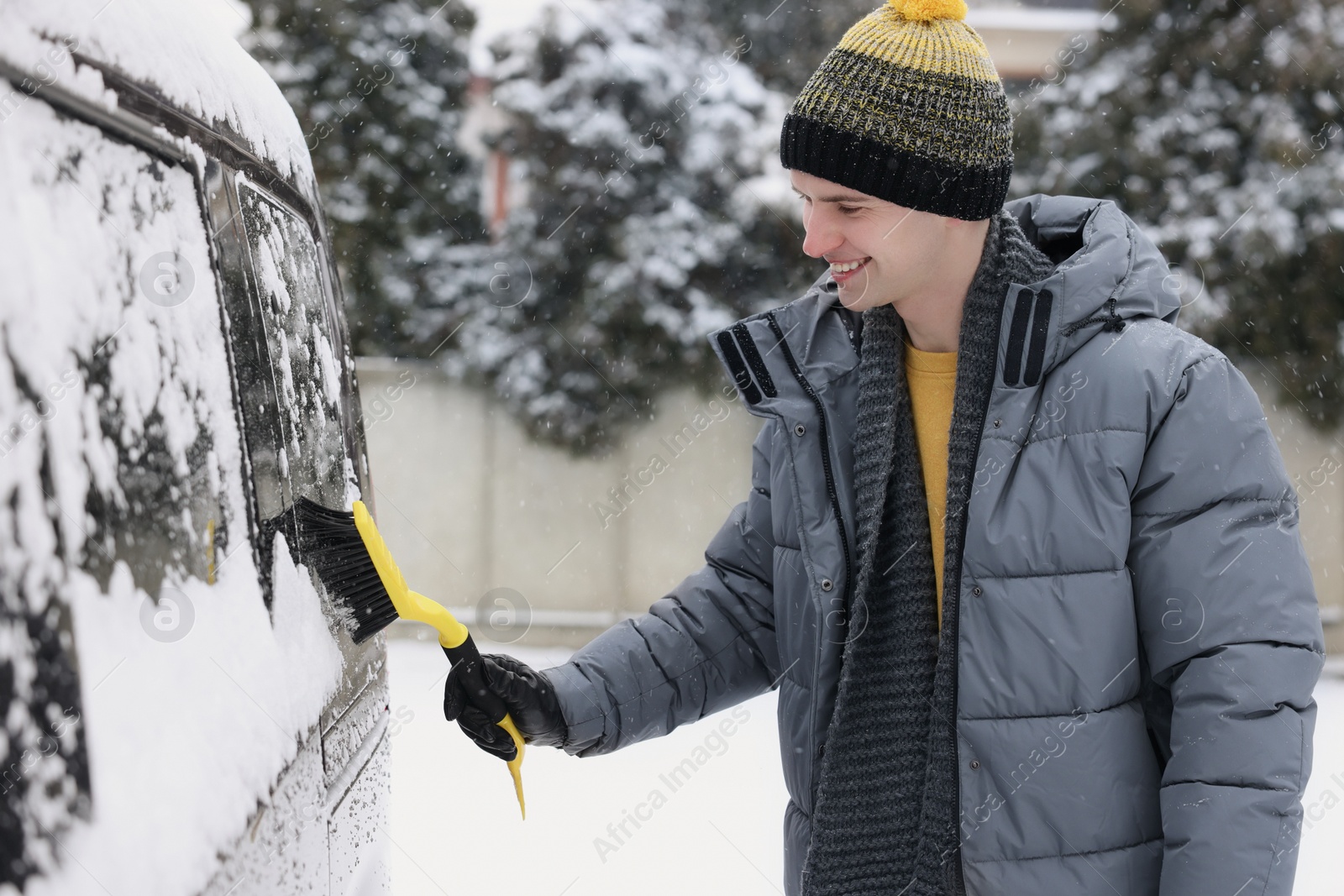 Photo of Man cleaning snow from car window outdoors