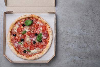 Photo of Delicious pizza Diablo in cardboard box on grey table, top view. Space for text
