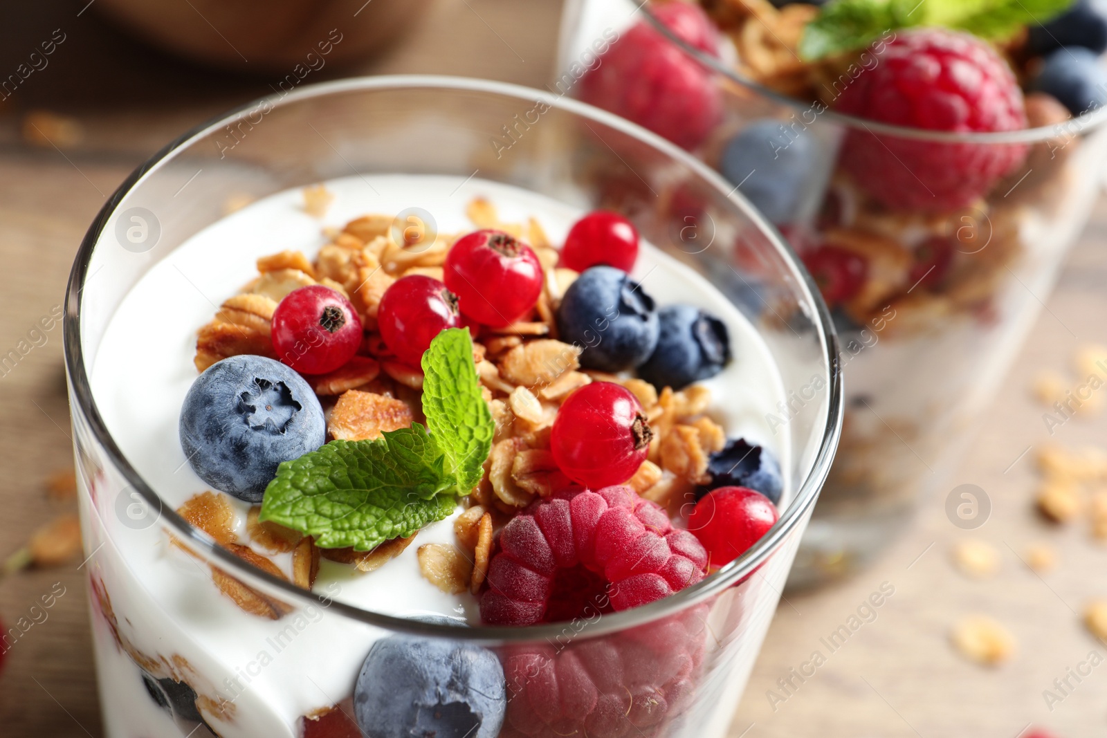 Image of Tasty dessert with yogurt, berries and granola on wooden table, closeup