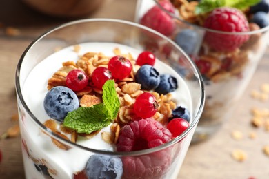 Tasty dessert with yogurt, berries and granola on wooden table, closeup