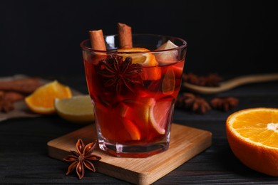 Photo of Glass of aromatic punch drink and ingredients on wooden table, closeup