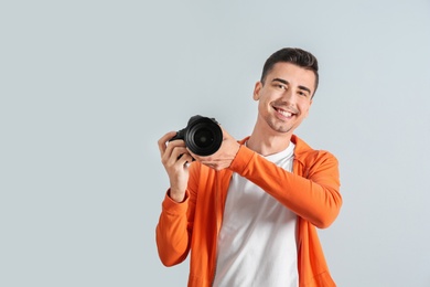 Photo of Male photographer with camera on light background