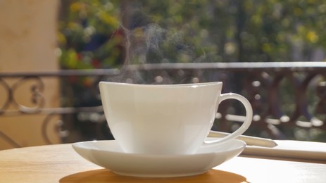 Cup of aromatic coffee on wooden table outdoors, closeup