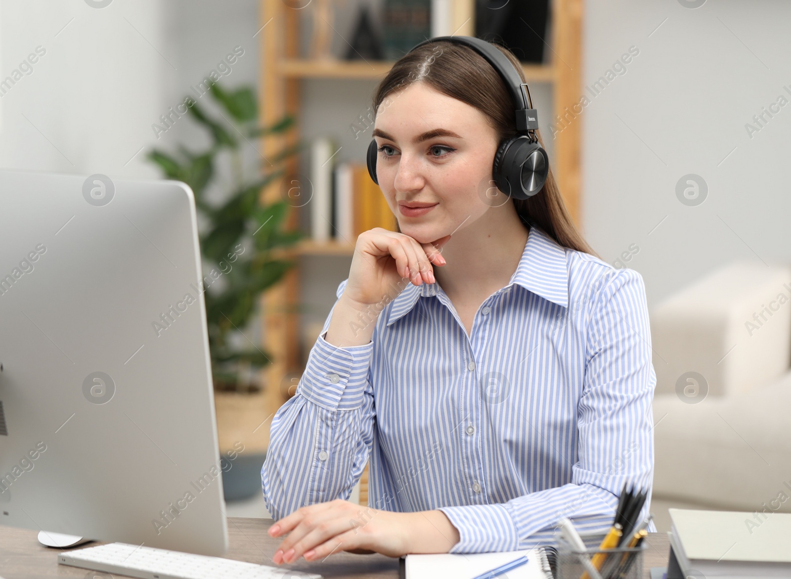 Photo of E-learning. Young woman using computer during online lesson at table indoors