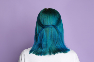 Photo of Woman with bright dyed hair on lilac background, back view