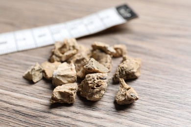 Photo of Pile of kidney stones on wooden table, closeup