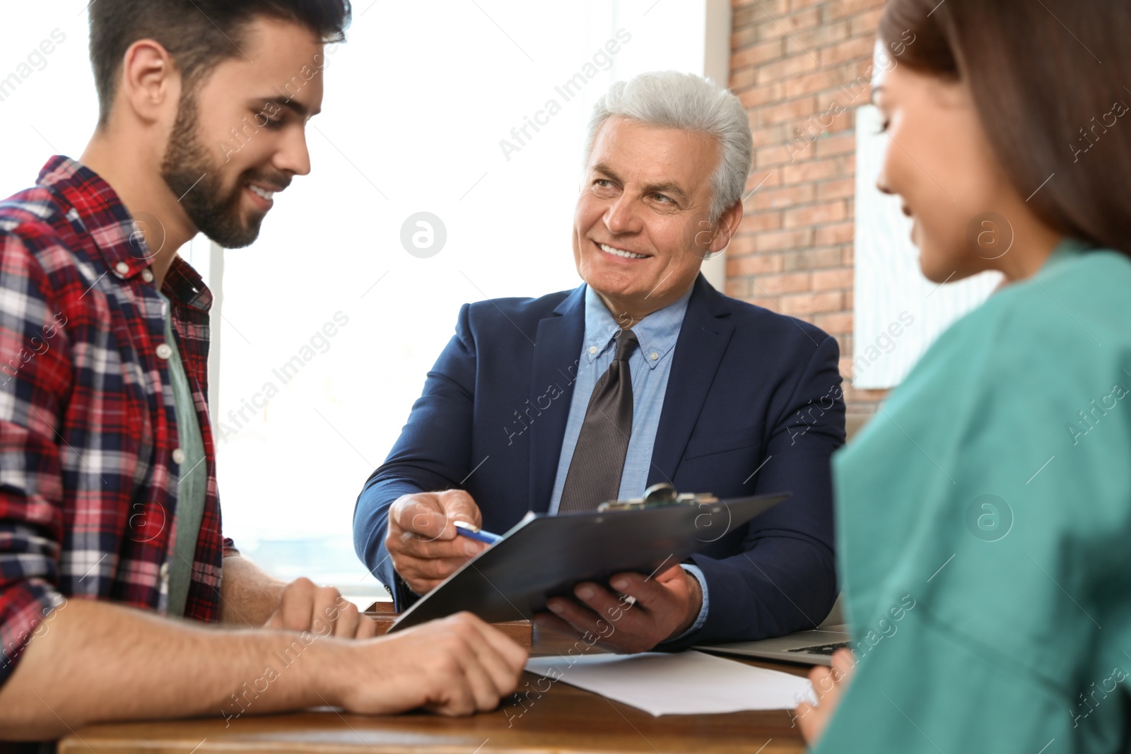 Photo of Senior notary working with young couple in office