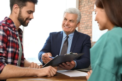 Senior notary working with young couple in office