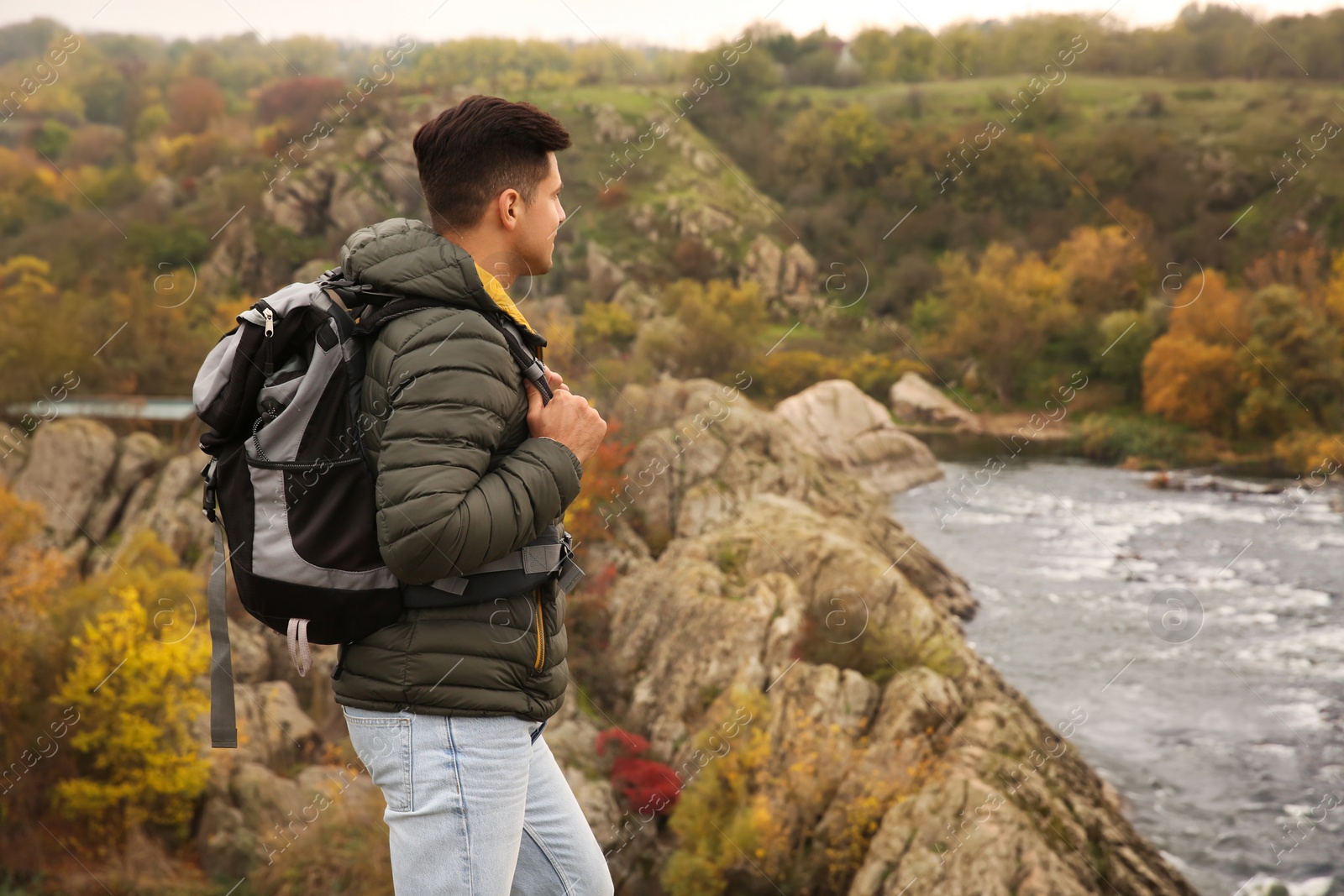 Photo of Traveler with backpack enjoying beautiful view near mountain river. Autumn vacation