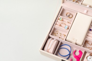 Photo of Jewelry box with many different accessories on light background, above view. Space for text