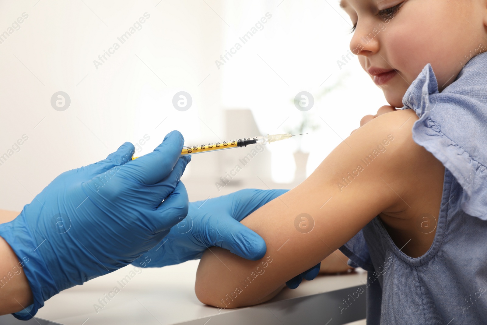 Photo of Doctor giving injection to little girl in hospital. Immunization concept