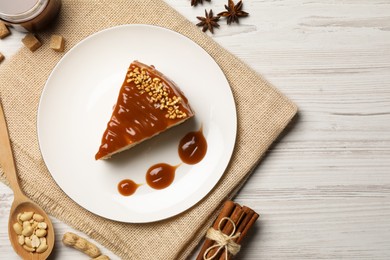 Tasty cheesecake with caramel and nuts served on white wooden table, flat lay. Space for text