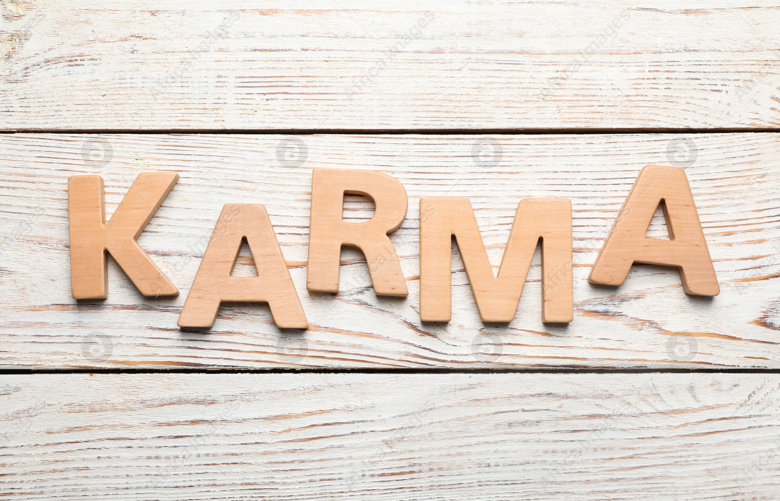 Photo of Word Karma made with letters on white wooden background, top view